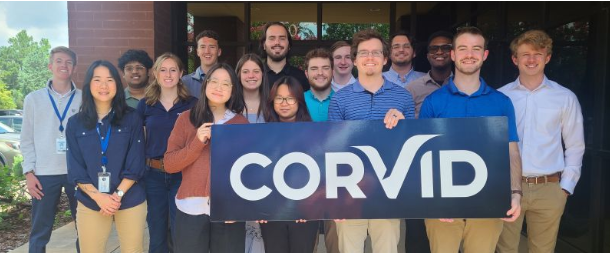Corvid Technologies intern cohort with company sign outside the Huntsville office, summer 2024